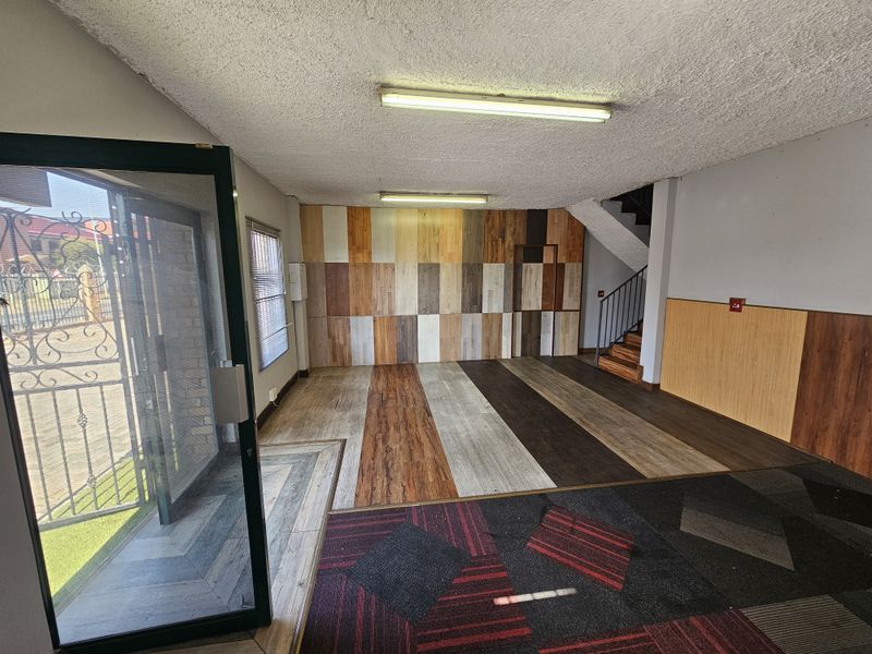 Spacious retail entry area featuring mixed flooring finishes, wood-paneled feature wall, and an internal staircase with metal handrail.