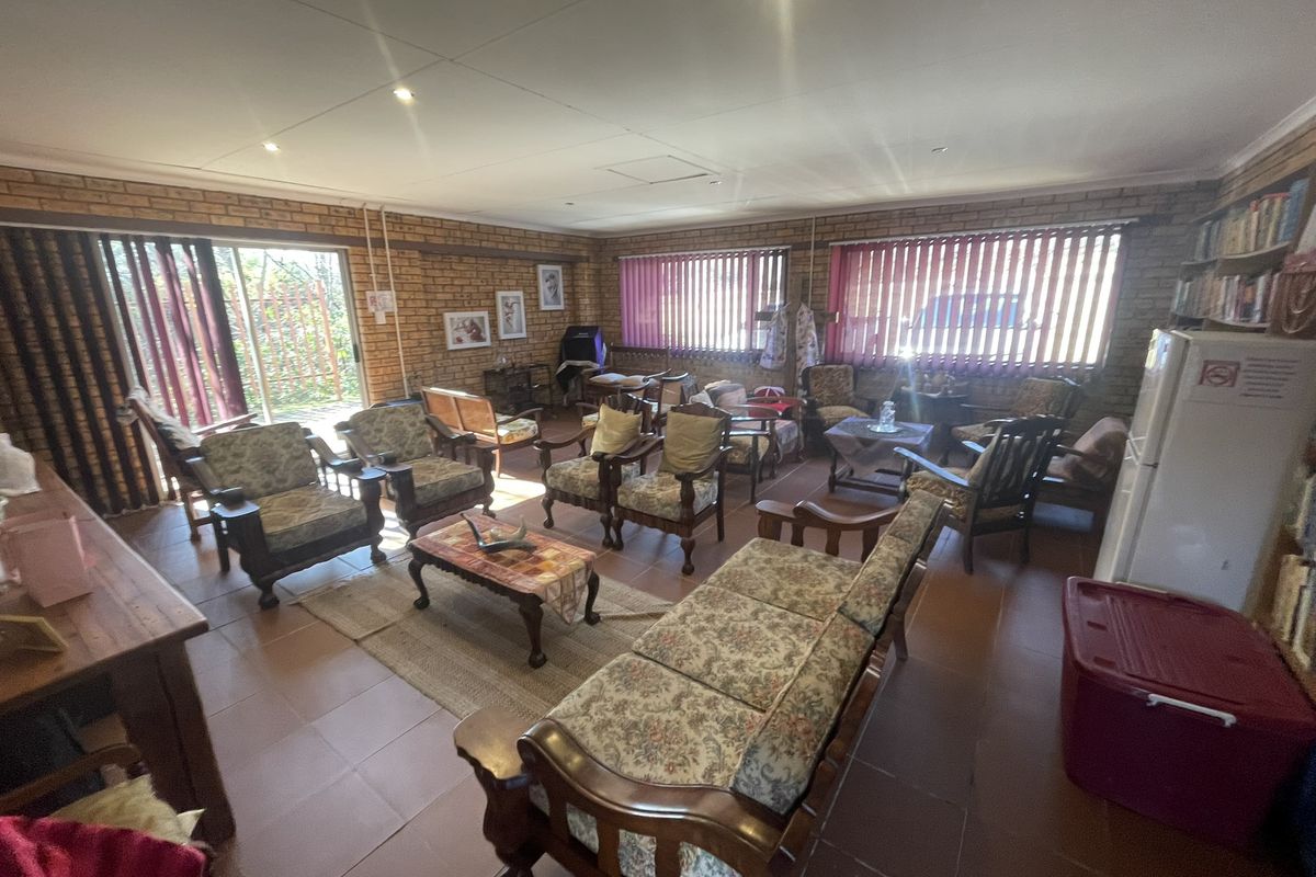 Spacious living area featuring exposed brick walls, tiled flooring, and large sliding glass doors providing access to the exterior.