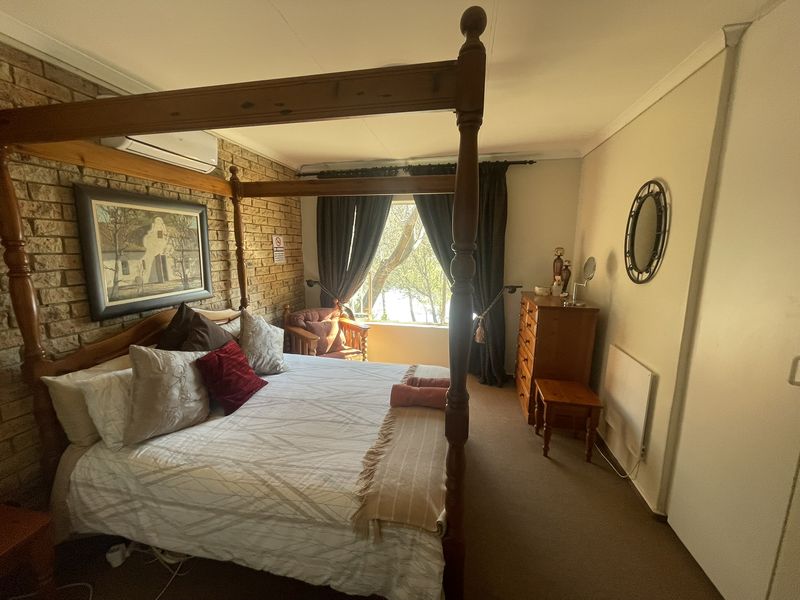 A bedroom featuring an exposed brick feature wall, built-in wardrobe, wall-mounted heater, and a split-system air conditioning unit.