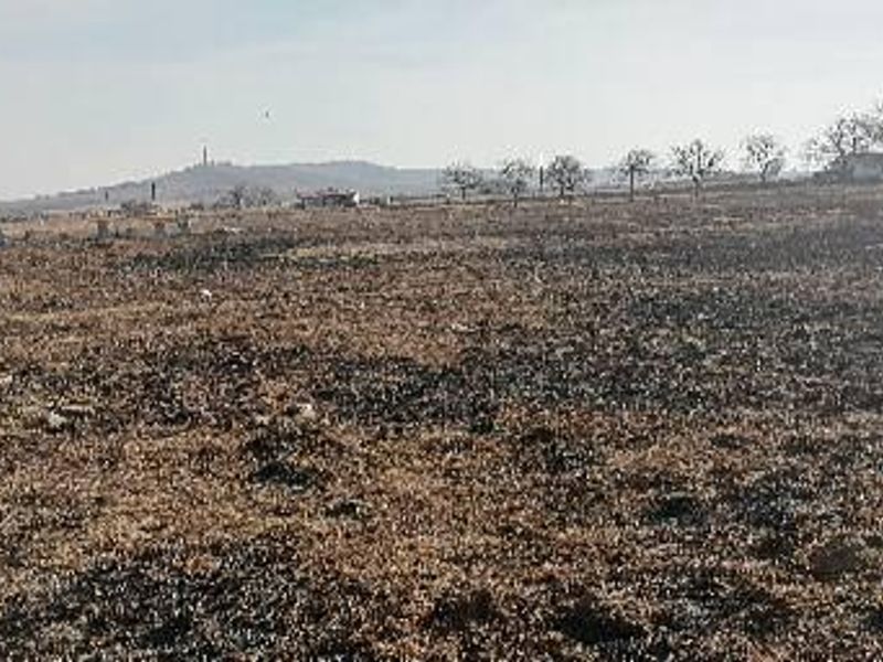 A wide-angle view of a vacant commercial land plot featuring dry, burnt vegetation across the terrain.