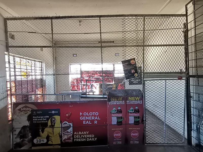 A secure utility or storage area featuring chain-link fencing, a security gate, and concrete flooring, suitable for commercial storage or operational use.
