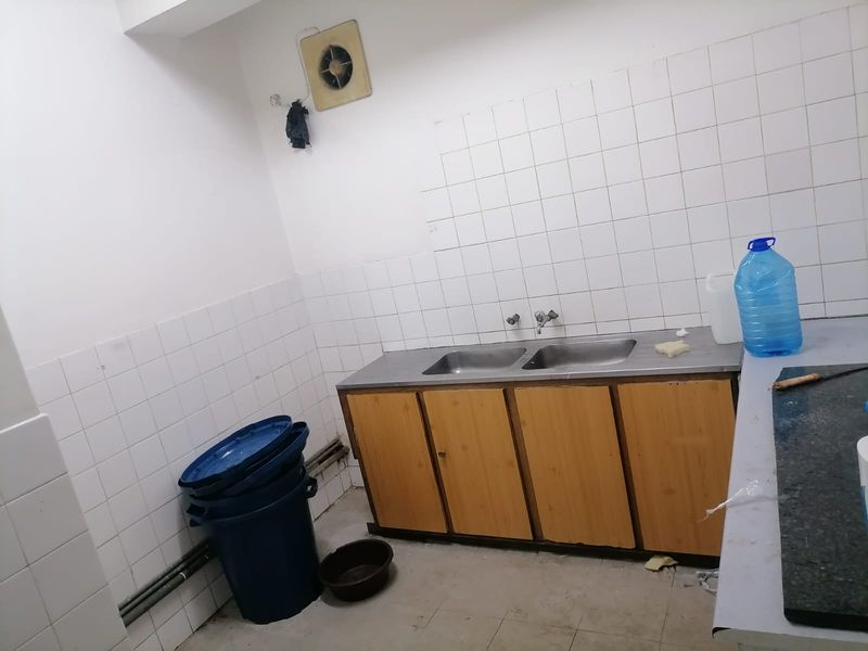 A functional scullery area featuring a double stainless steel sink, tiled splashback, and built-in wooden cabinetry, suitable for utility or prep work.