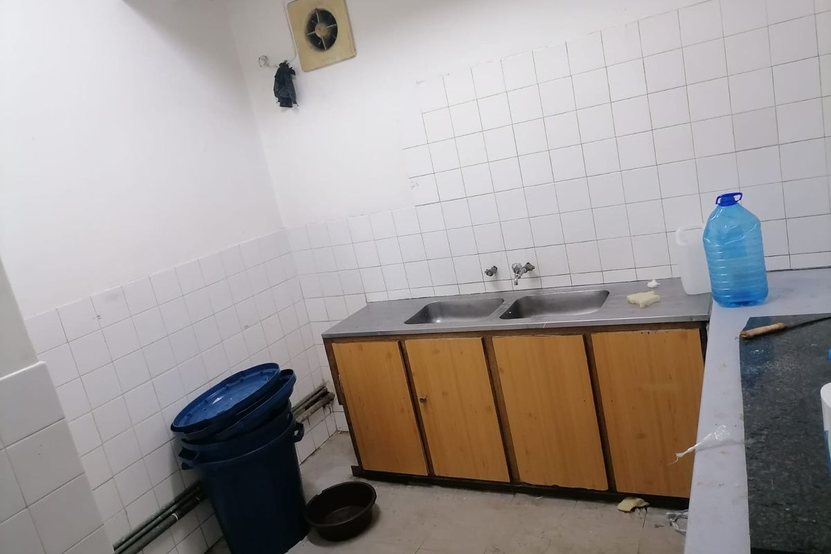 A functional scullery area featuring a double stainless steel sink, tiled splashback, and built-in wooden cabinetry, suitable for utility or prep work.
