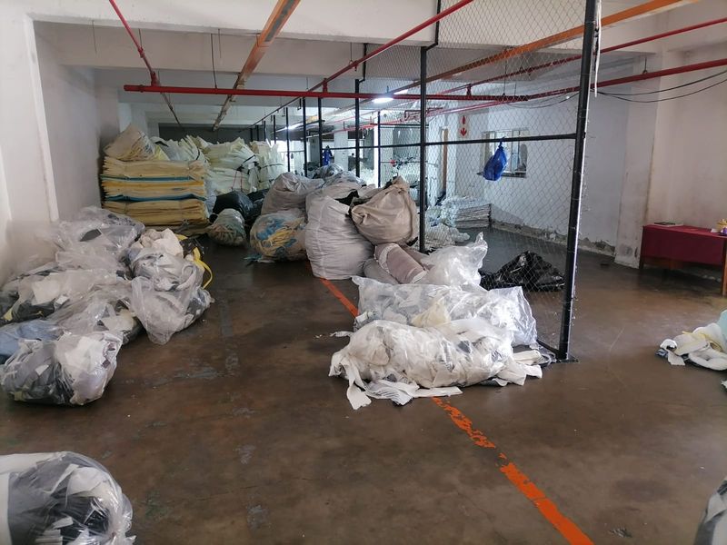 Industrial utility or storage space featuring exposed fire sprinkler systems, concrete flooring, and chain-link security partitioning.