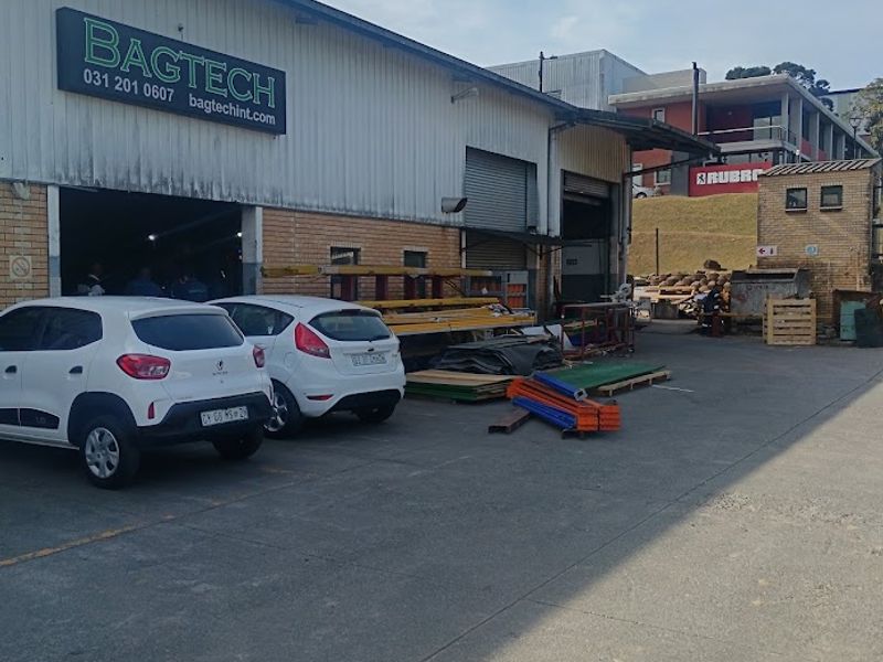 Industrial warehouse exterior featuring corrugated metal cladding, roller shutter access doors, and a concrete yard area suitable for logistics or manufacturing operations.
