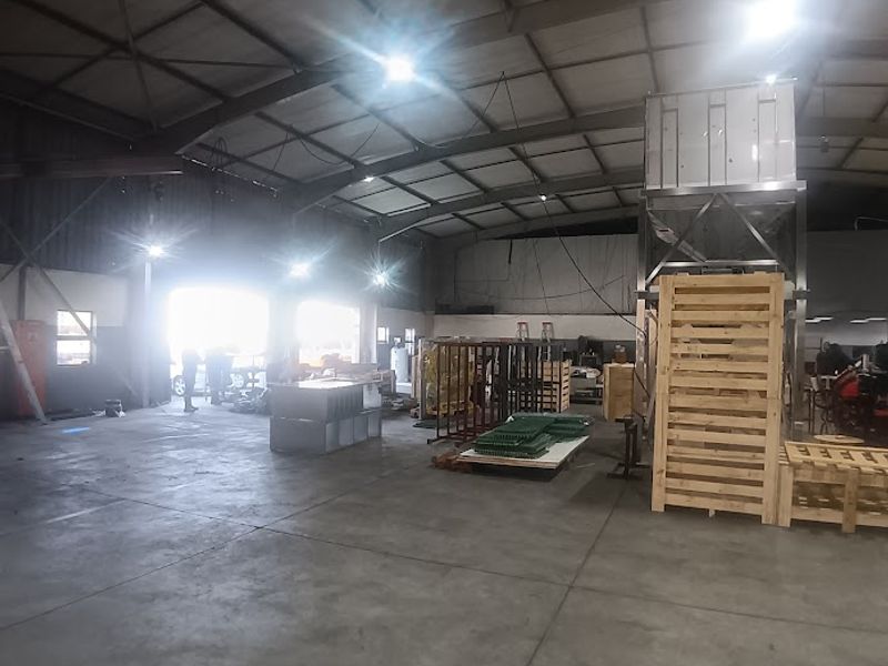 Spacious industrial warehouse unit featuring high ceilings with exposed steel trusses, polished concrete flooring, and large roller shutter access doors.