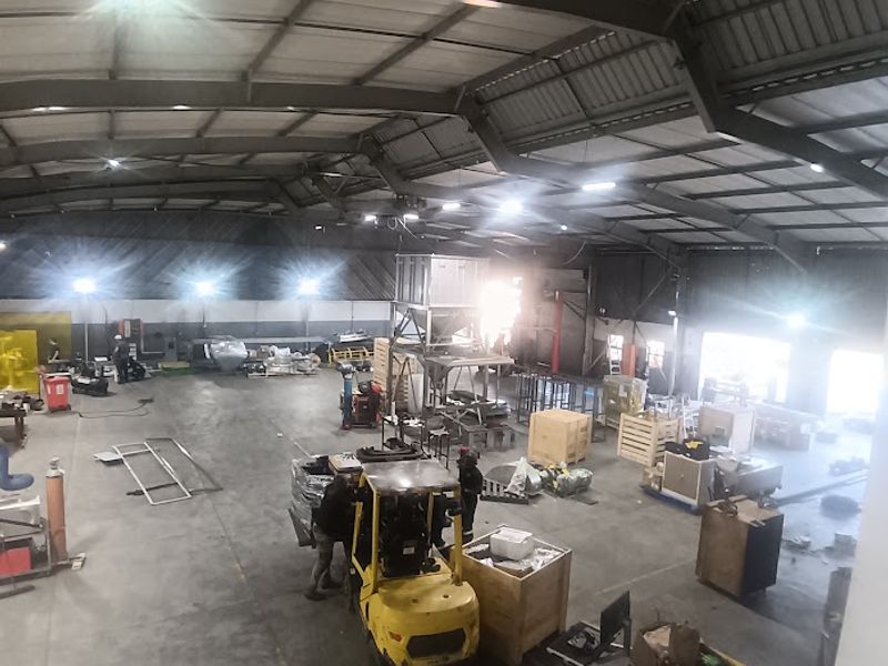 Spacious industrial warehouse featuring a steel portal frame structure, concrete flooring, and high-bay lighting, suitable for manufacturing or storage operations.