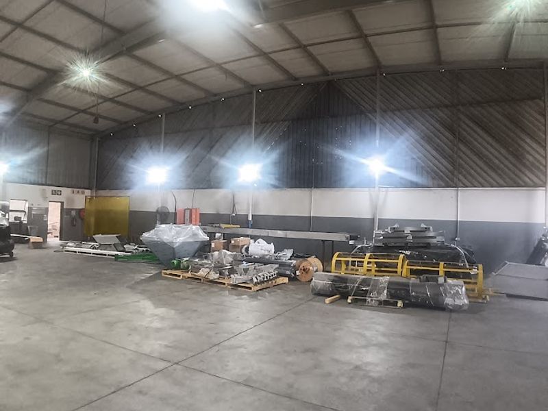 Spacious industrial warehouse unit featuring high ceilings with exposed steel trusses, durable concrete flooring, and functional industrial lighting throughout the open floor plan.