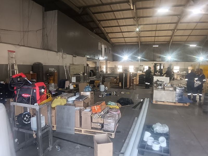 Spacious industrial warehouse area featuring high-bay ceilings, exposed steel trusses, and durable concrete flooring, suitable for various commercial or manufacturing operations.