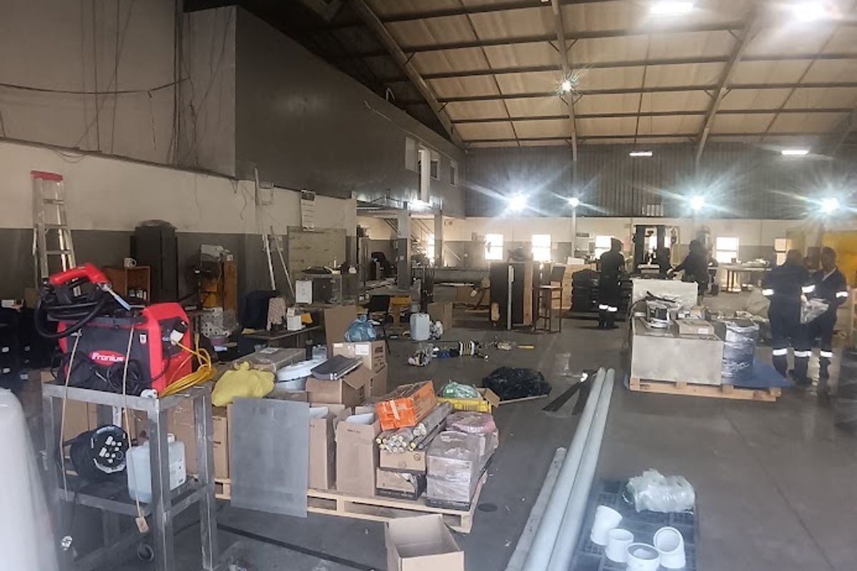 Spacious industrial warehouse area featuring high-bay ceilings, exposed steel trusses, and durable concrete flooring, suitable for various commercial or manufacturing operations.