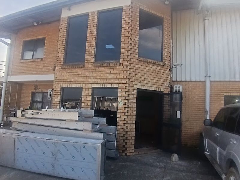 Front elevation of an industrial building featuring face brick construction, aluminium windows, and a concrete driveway area.