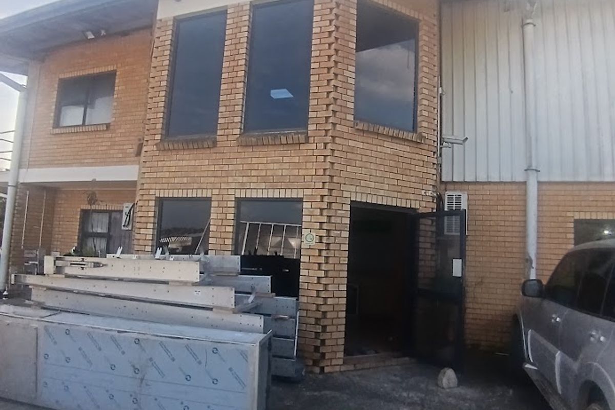 Front elevation of an industrial building featuring face brick construction, aluminium windows, and a concrete driveway area.