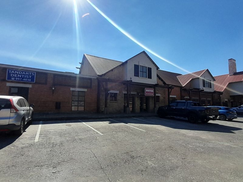 Front exterior view of a commercial office complex featuring brick facades, metal roofing, and dedicated parking spaces.