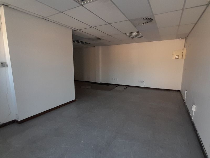 An empty, open-plan office space featuring a suspended ceiling, recessed air conditioning, and multiple electrical and data points.