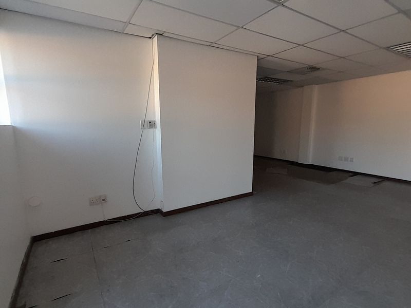 An empty office space featuring a suspended ceiling, recessed lighting, and tiled flooring, ready for custom fit-out and configuration.