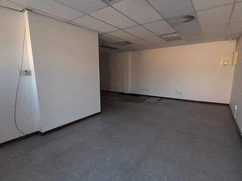 An empty, open-plan office space featuring a suspended ceiling, recessed lighting, and integrated air conditioning, requiring minor repairs to flooring and electrical finishes.