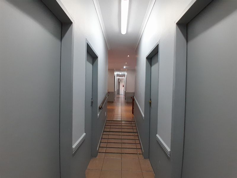 A functional office hallway featuring tiled flooring, neutral wall finishes, and integrated lighting, providing access to multiple office rooms.