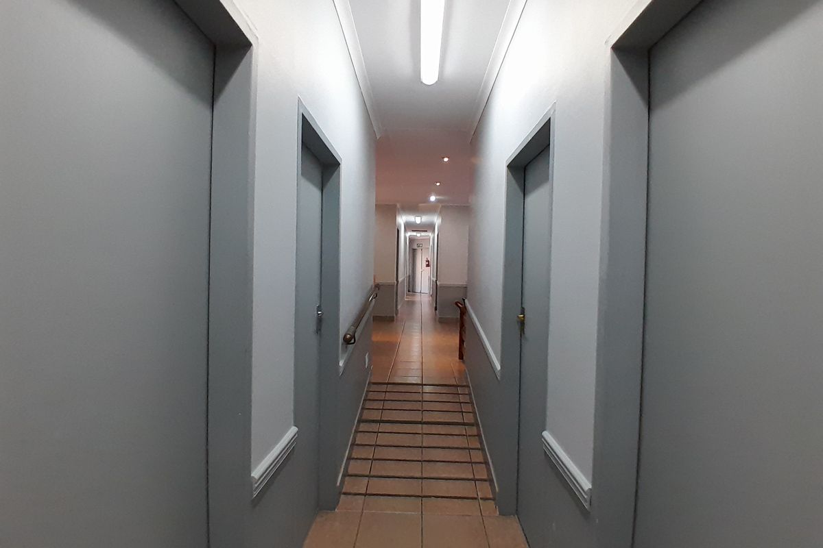 A functional office hallway featuring tiled flooring, neutral wall finishes, and integrated lighting, providing access to multiple office rooms.
