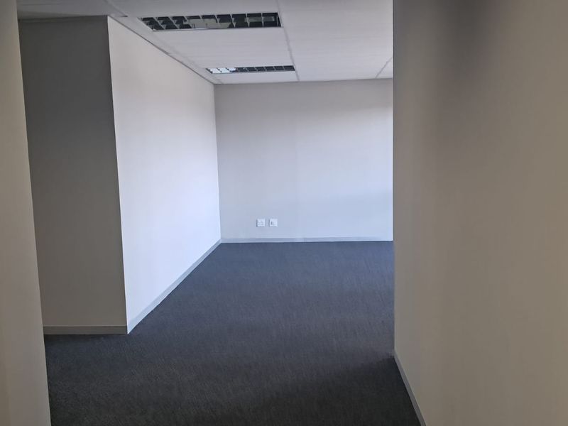 A vacant, well-maintained office space featuring neutral walls, carpeted flooring, and a suspended ceiling with recessed lighting.