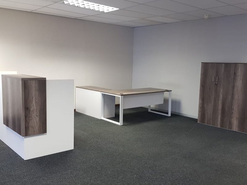 A clean, professional office space featuring a suspended ceiling, recessed lighting, and neutral carpeting, suitable for a modern workspace environment.