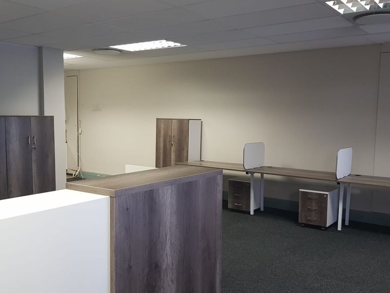 A professional office space featuring a suspended ceiling, recessed lighting, fitted cabinetry, and built-in desk workstations with carpeted flooring.