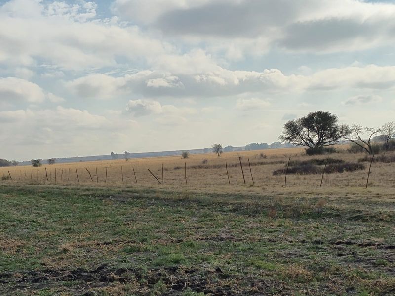 A wide-angle view of the expansive farm landscape featuring open fields and traditional wire boundary fencing.