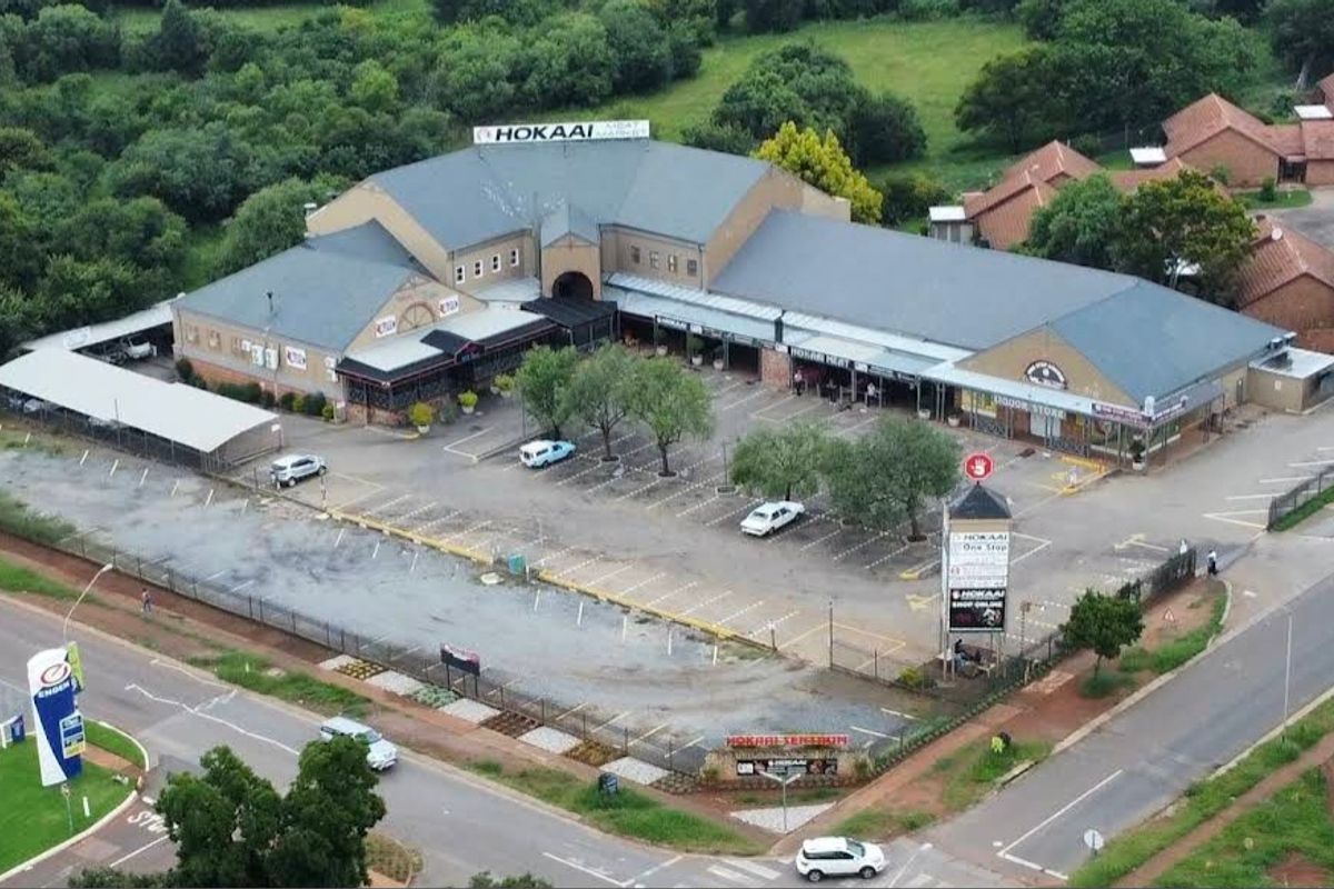 Aerial view of a commercial office and retail complex featuring a large asphalt parking area, covered parking bays, and landscaped grounds.