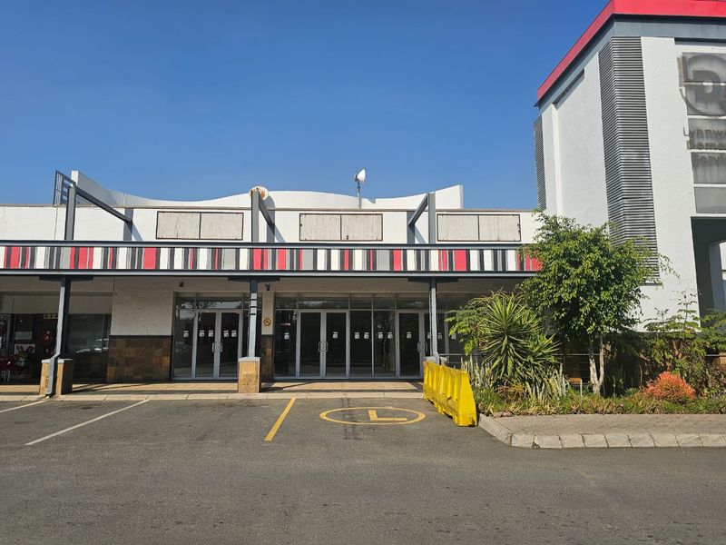 Front facade of a retail property featuring glass entrance doors, a covered walkway, and dedicated parking space.