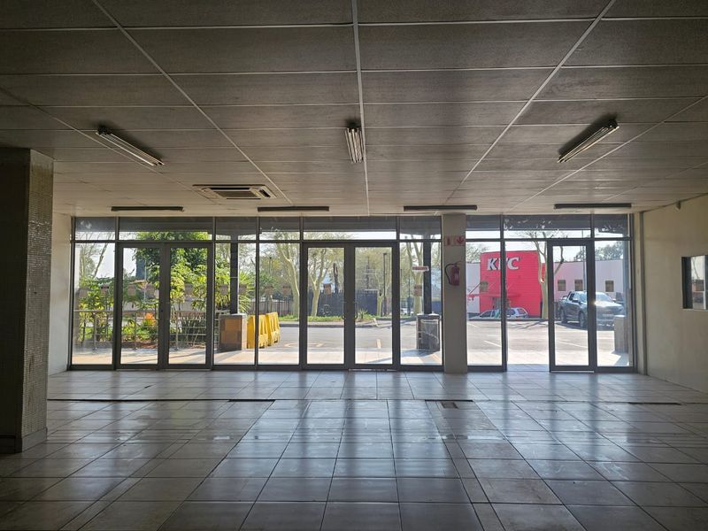 Spacious open-plan retail unit featuring large glass storefront windows, tiled flooring, and a suspended ceiling, offering excellent visibility and natural light.