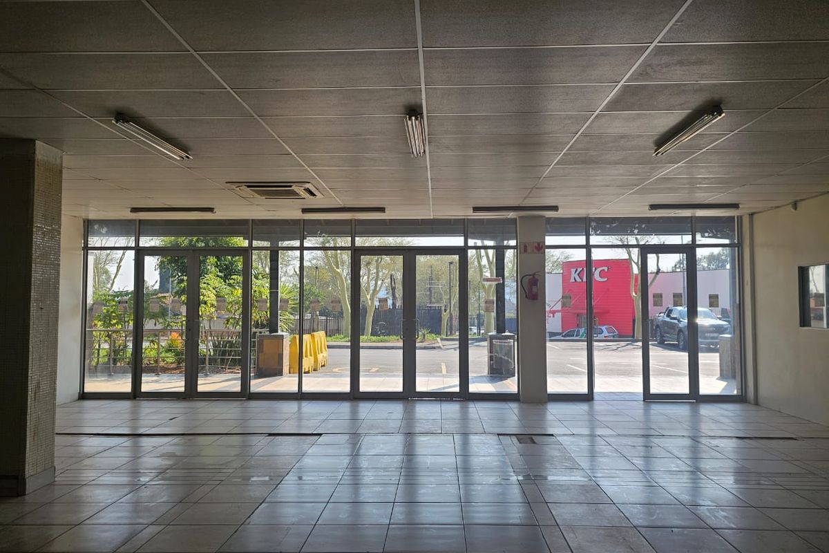 Spacious open-plan retail unit featuring large glass storefront windows, tiled flooring, and a suspended ceiling, offering excellent visibility and natural light.