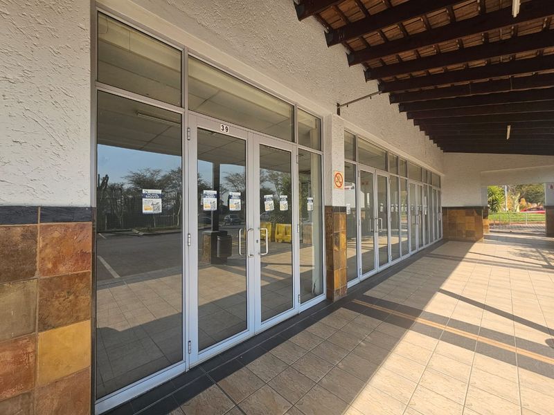 A retail storefront featuring an aluminium-framed glass facade, tiled walkway, and covered veranda area, suitable for commercial use.