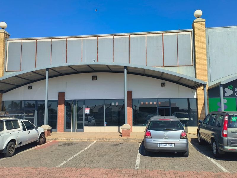 Front elevation of a retail unit featuring a curved metal awning, glass storefront, and dedicated paved parking space.