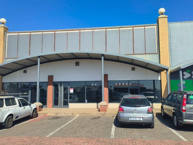 Front elevation of a retail unit featuring a curved metal awning, glass storefront, and dedicated paved parking space.