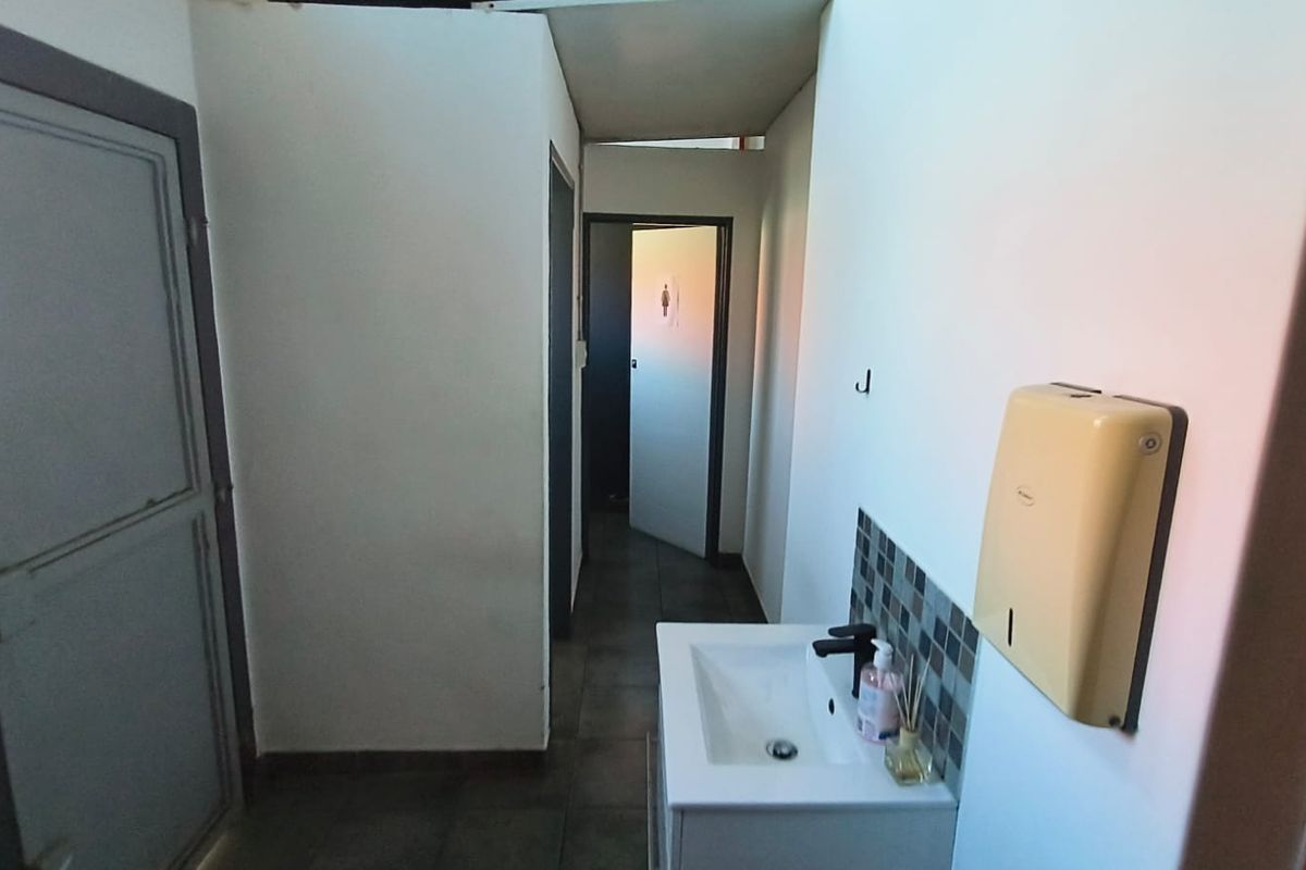A functional bathroom area featuring a wall-mounted basin with a tiled splashback and a wall-mounted paper towel dispenser.