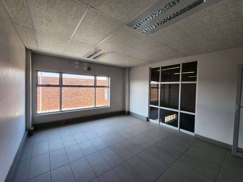 Empty office space featuring tiled flooring, suspended ceiling with recessed lighting, and an internal glass partition, suitable for a professional workspace.