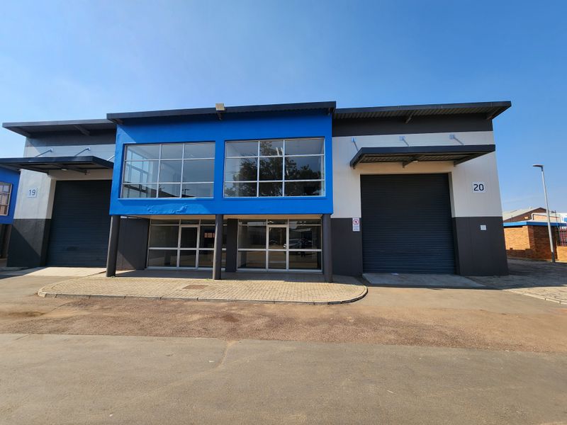Modern industrial unit featuring large roller shutter doors, expansive glass frontage, and a paved exterior approach, suitable for warehouse or commercial operations.
