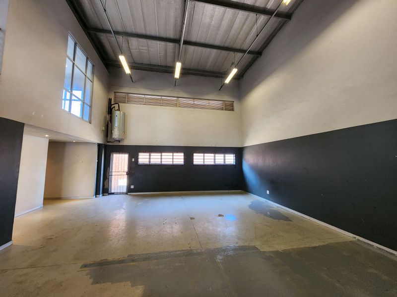 Spacious industrial utility area featuring high ceilings, exposed steel structure, concrete flooring, and an integrated electric water heater.