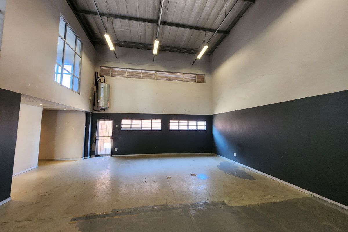 Spacious industrial utility area featuring high ceilings, exposed steel structure, concrete flooring, and an integrated electric water heater.