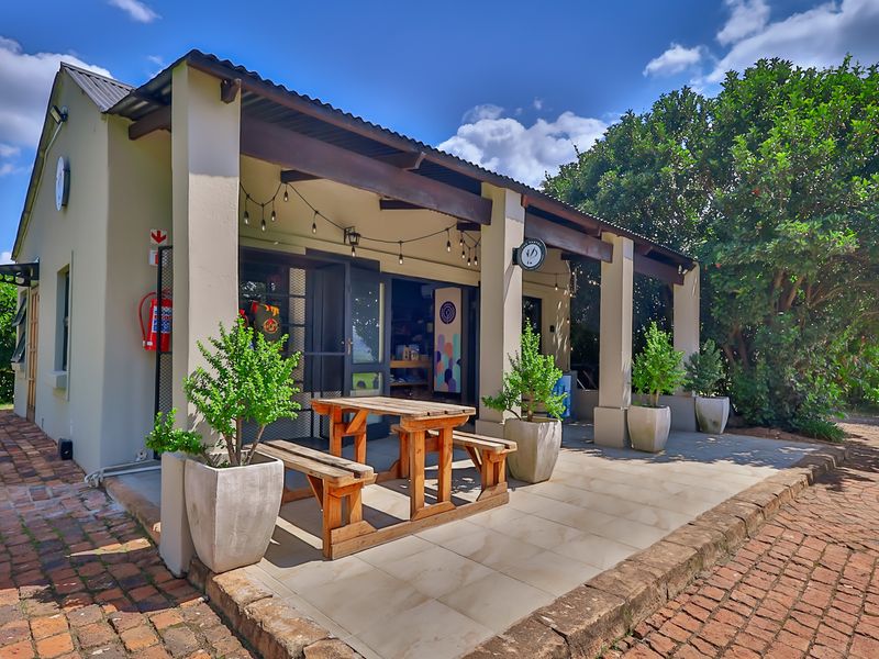 A well-maintained covered patio area featuring tiled flooring, exposed timber beams, and direct access to the building interior.