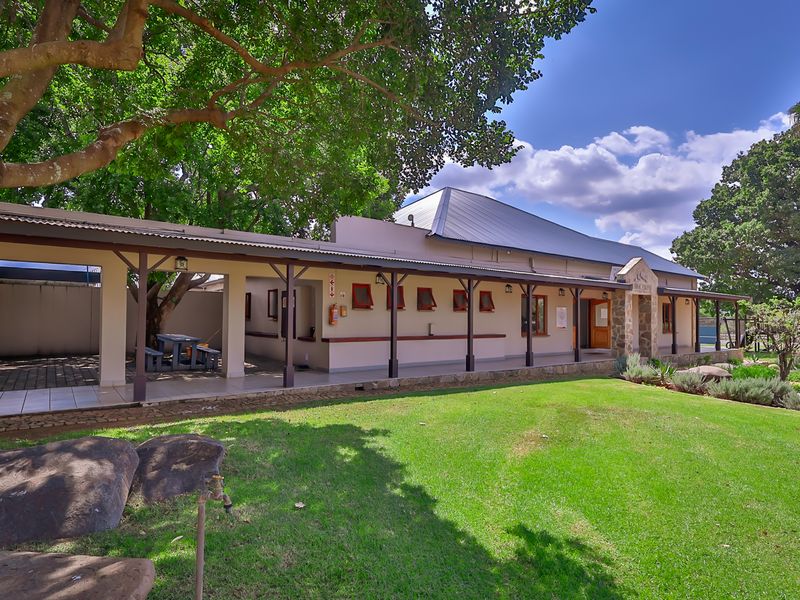 A well-maintained industrial property featuring a spacious covered patio area, stone architectural details, and a large landscaped lawn.