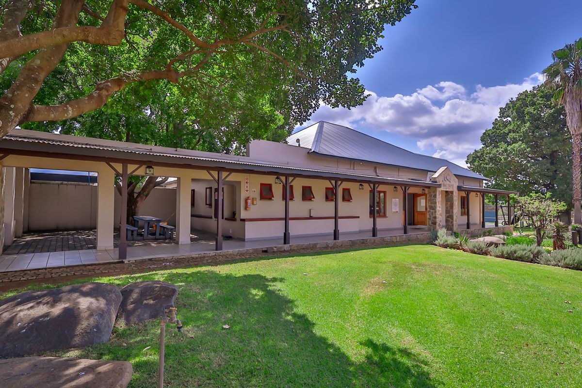 A well-maintained industrial property featuring a spacious covered patio area, stone architectural details, and a large landscaped lawn.