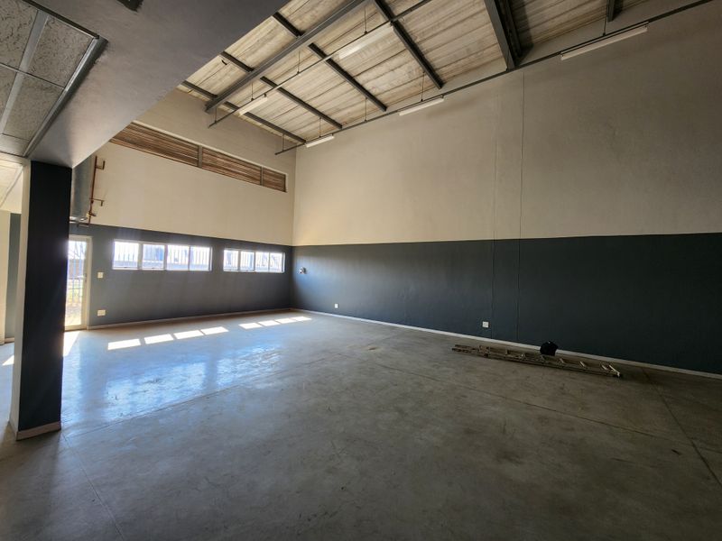 Spacious industrial utility area featuring high ceilings with exposed steel trusses, polished concrete flooring, and ample natural light through high-level windows.
