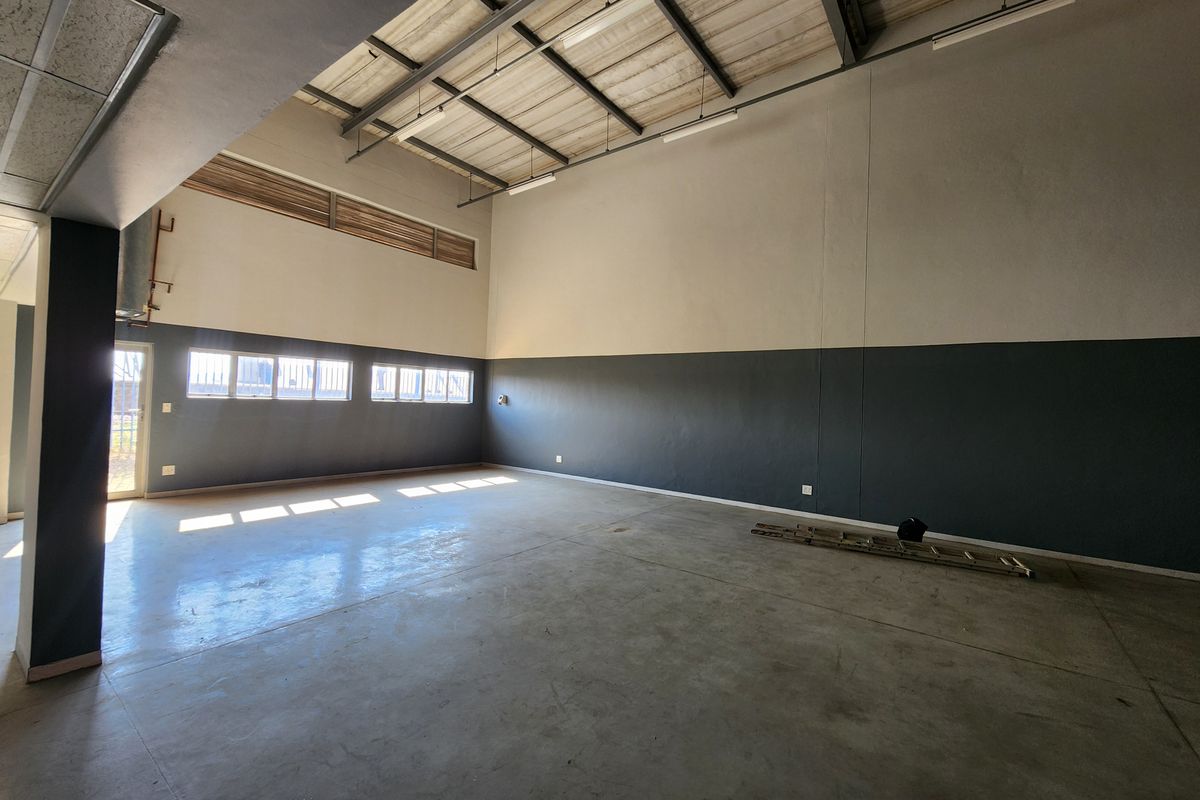 Spacious industrial utility area featuring high ceilings with exposed steel trusses, polished concrete flooring, and ample natural light through high-level windows.