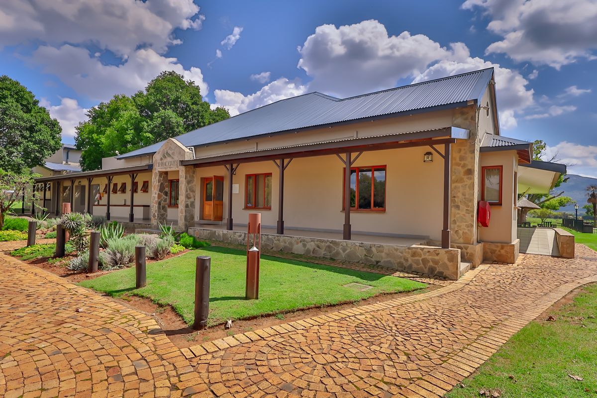 A well-maintained industrial-style building featuring stone cladding, a covered veranda with timber posts, and attractive cobblestone paving in a landscaped setting.