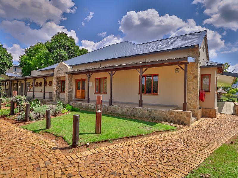 A well-maintained industrial-style building featuring stone cladding, a covered veranda with timber posts, and attractive cobblestone paving in a landscaped setting.