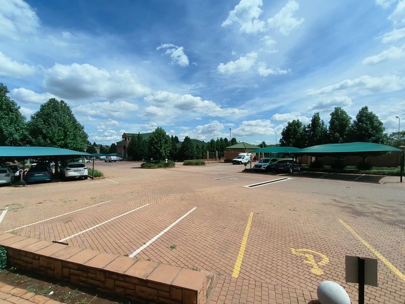 Spacious paved office parking area featuring multiple shade cloth carports and clearly marked parking bays.
