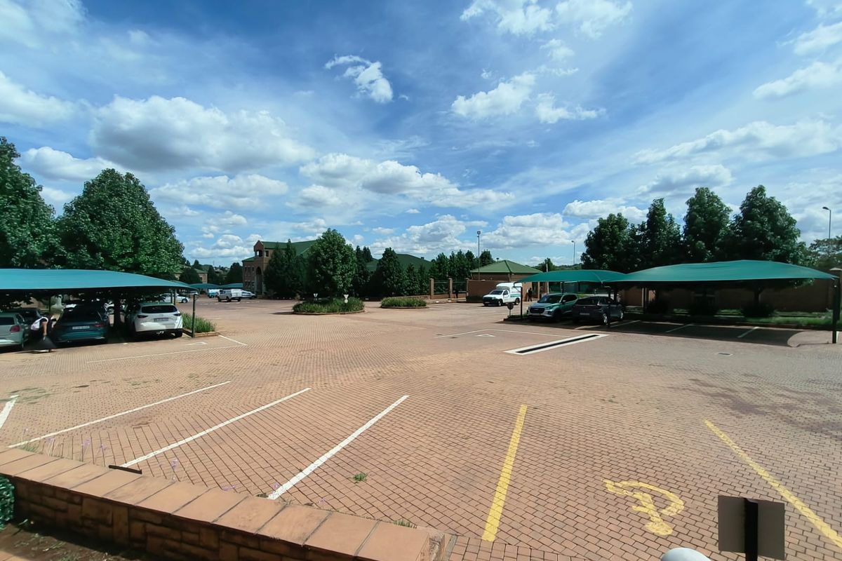Spacious paved office parking area featuring multiple shade cloth carports and clearly marked parking bays.