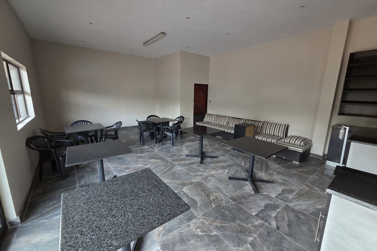 A spacious office area featuring large format floor tiles, recessed and fluorescent lighting, and built-in shelving units.