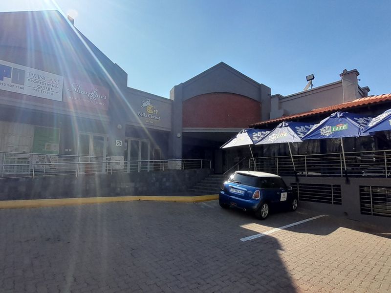 Front facade of a commercial retail property featuring paved parking, stainless steel railings, and multiple storefront signage areas.