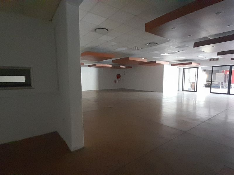 Spacious open-plan retail area featuring a suspended ceiling with recessed lighting, polished concrete floors, and large glass sliding doors providing ample natural light.